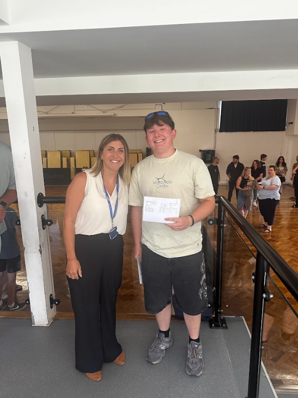 A male Post-16 student is pictured smiling for the camera alongside a female member of staff, after having just opened his A-Level results.