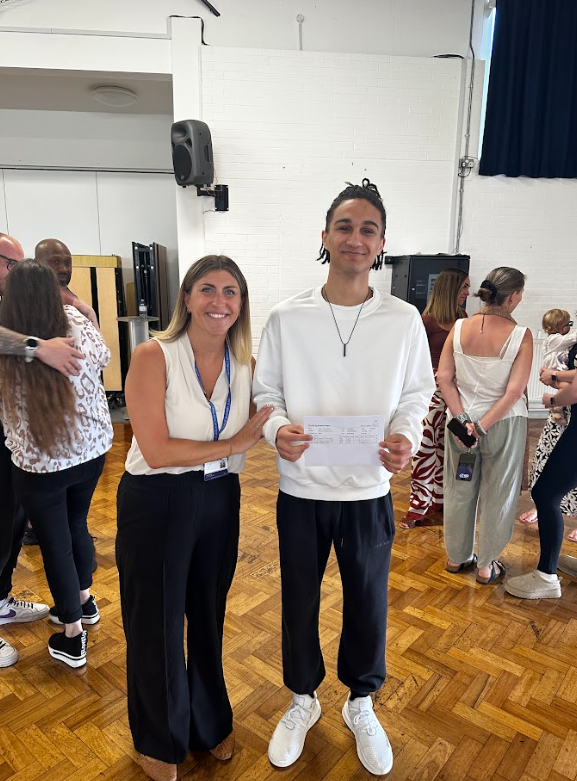 A male Post-16 student is pictured smiling for the camera alongside a female member of staff, after having just opened his A-Level results.